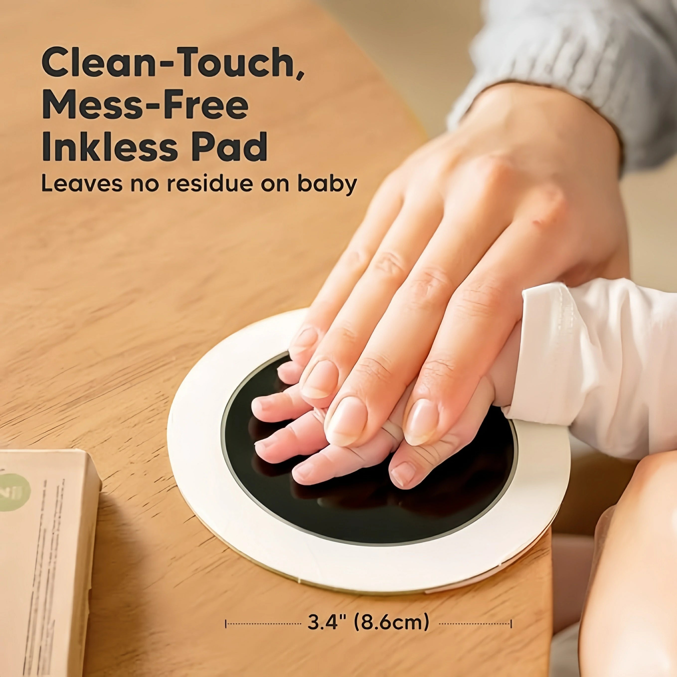 Close-up of an adult hand gently pressing a baby's hand onto a round Clean-Touch inkless pad. Text reads "Mess-Free Inkless Pad, Leaves no residue". Shows 3.4 inch (8.6cm) size. Demonstrates safety for sensitive skin and paws.