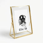 A touching pet memorial keepsake featuring a custom dog nose print stamped in black ink on white paper, floating inside a luxury gold metal glass frame. The personalized artwork includes the pet's name and year. Designed as a bereavement gift for loss of a dog, this standing photo frame elegantly showcases the unique details of a pet's nose, offering a lasting tribute and comfort for pet parents dealing with the loss of their best friend
