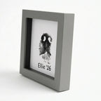 Angled profile of modern grey pet memorial shadow box frame showing deep display depth. Features unique dog nose print (snout print) with custom text 'Ellie '26'. Sleek grey finish and black inner matting create a perfect modern home decor tribute