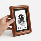 A touching pet sympathy gift: Hand holding a finished rosewood print frame. The smooth rounded edges and premium black mat create a dignified tribute. Perfect for keeping a personalized nose print of a beloved dog close to your heart.