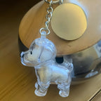 A transparent dog-shaped keychain from Larleaf, used as a memorial keepsake for storing pet fur. The pendant is shown filled with white dog hair and attached to a silver chain with a round metallic tag.