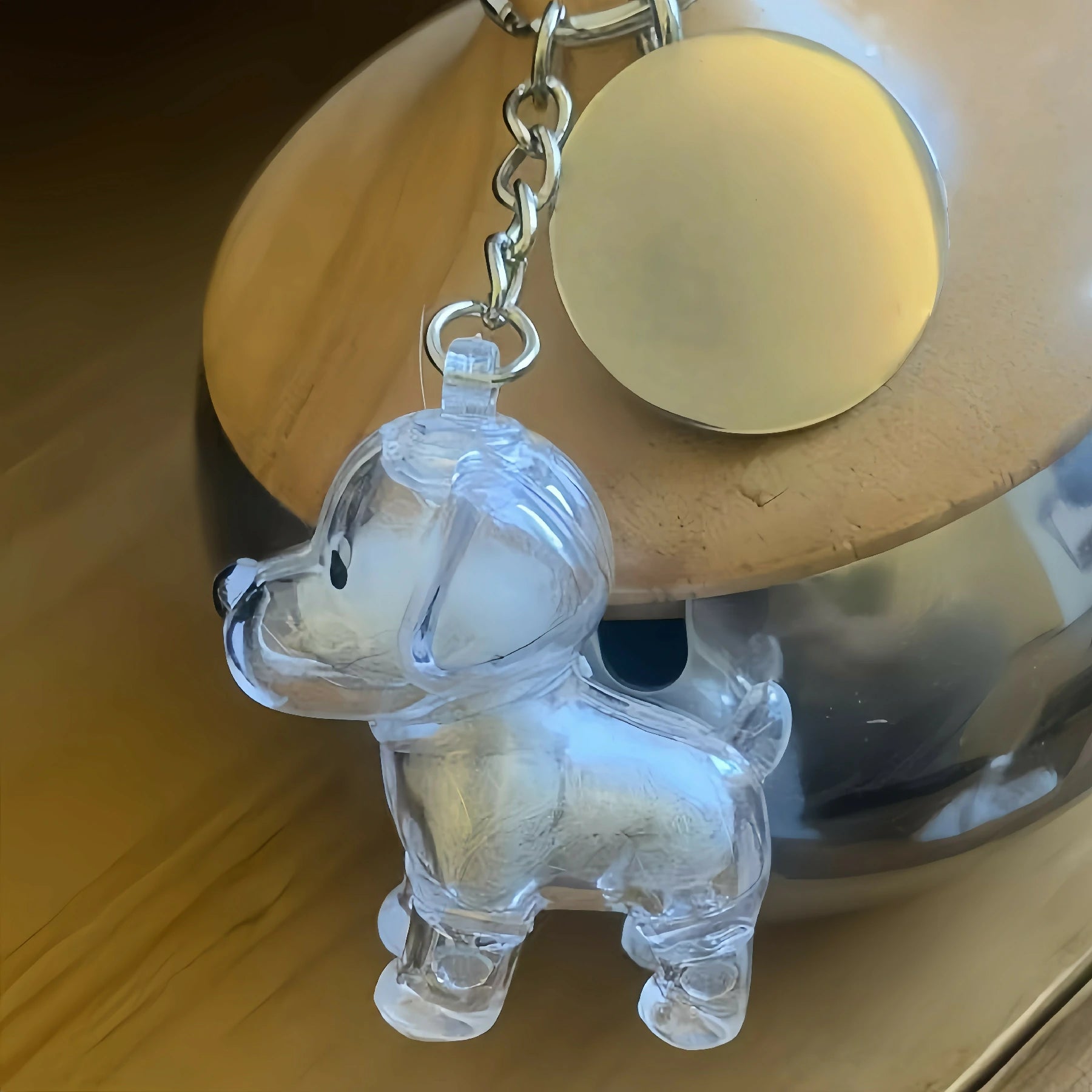 A transparent dog-shaped keychain from Larleaf, used as a memorial keepsake for storing pet fur. The pendant is shown filled with white dog hair and attached to a silver chain with a round metallic tag.