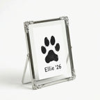 Freestanding silver memorial frame for a pet's paw print. Pictured from a 3/4 angle to show the elegant wire backing. The vintage floral details frame the artwork beautifully. A sophisticated sympathy gift for a desk or mantelpiece.