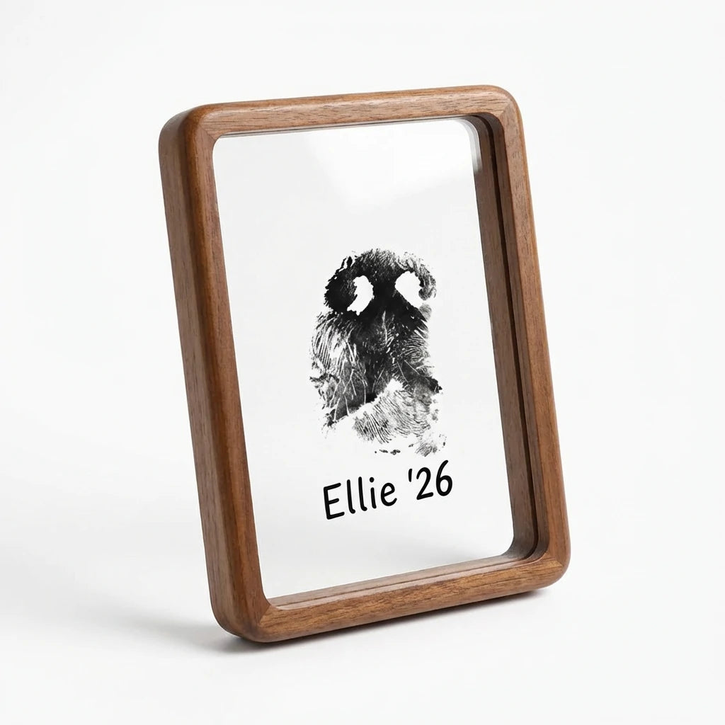 Angled view of premium walnut wood pet memorial frame featuring elegant rounded corners. Displays a unique dog nose print (snout print) with custom text 'Ellie '26'. This modern curved-edge design offers a sophisticated, organic tribute for pet loss